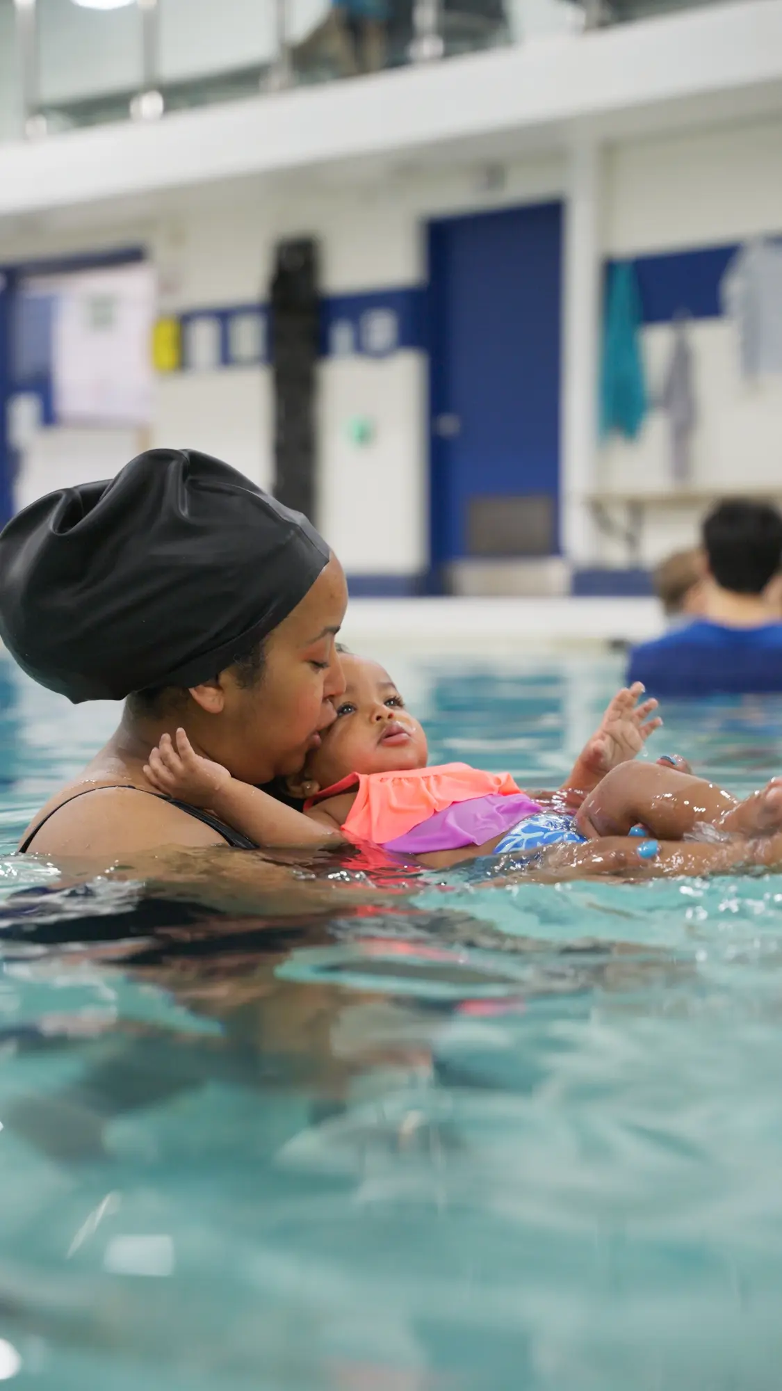 A parent holds their baby securely during a Seal Swimming class.